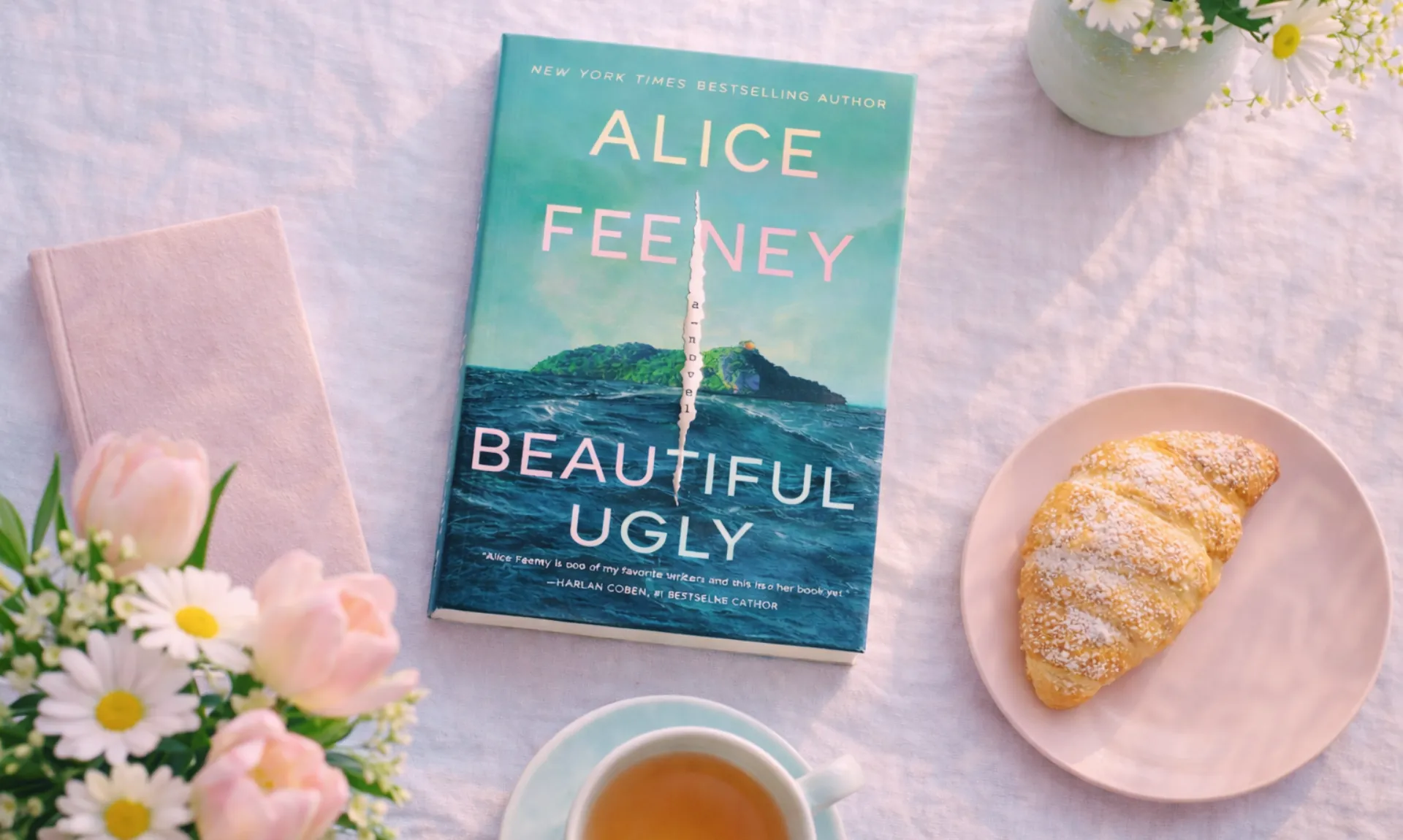 Beautiful Ugly by Alice Feeney placed on a light spring café-style table with tea, croissant, and flowers in soft natural daylight