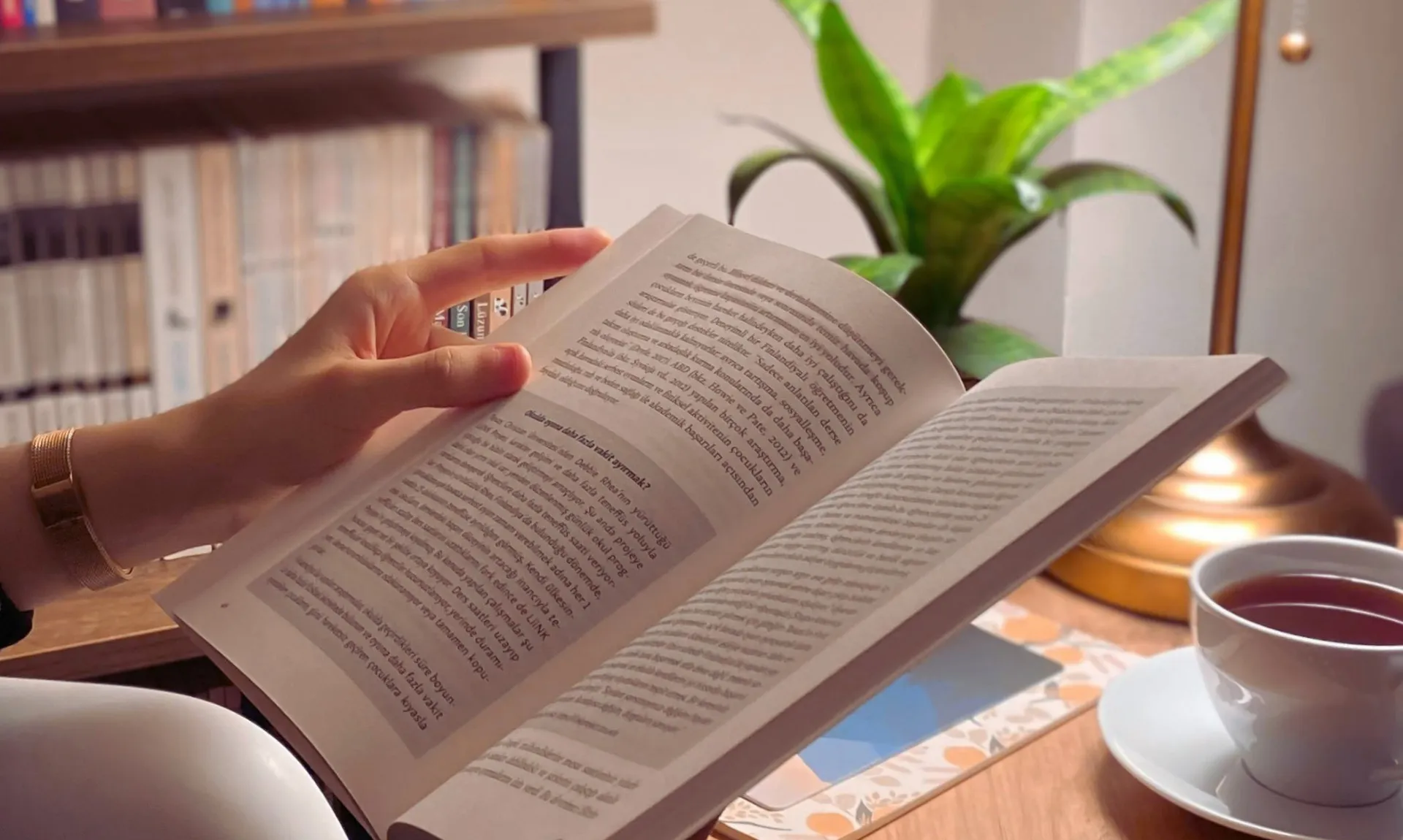 a person reading a book with book stacks in the background